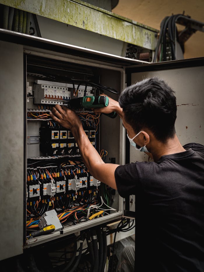 Mastering the First Impression: Your intriguing post title goes here Technician working on circuit breaker panel, adjusting electrical wires indoors.